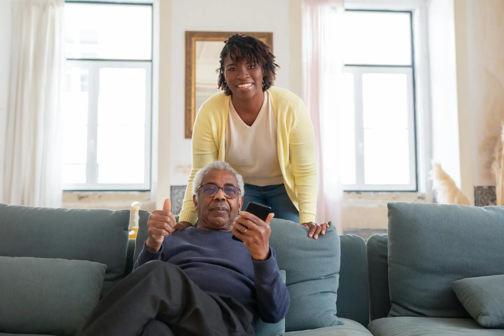 Smiling senior man and caregiver share a joyful moment at home.